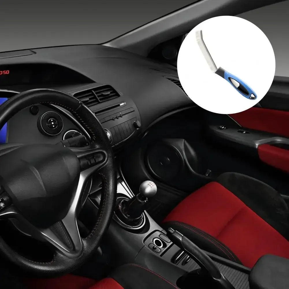 A close-up view of a hard bristle crevice cleaning brush with a blue handle shown in a car interior context.