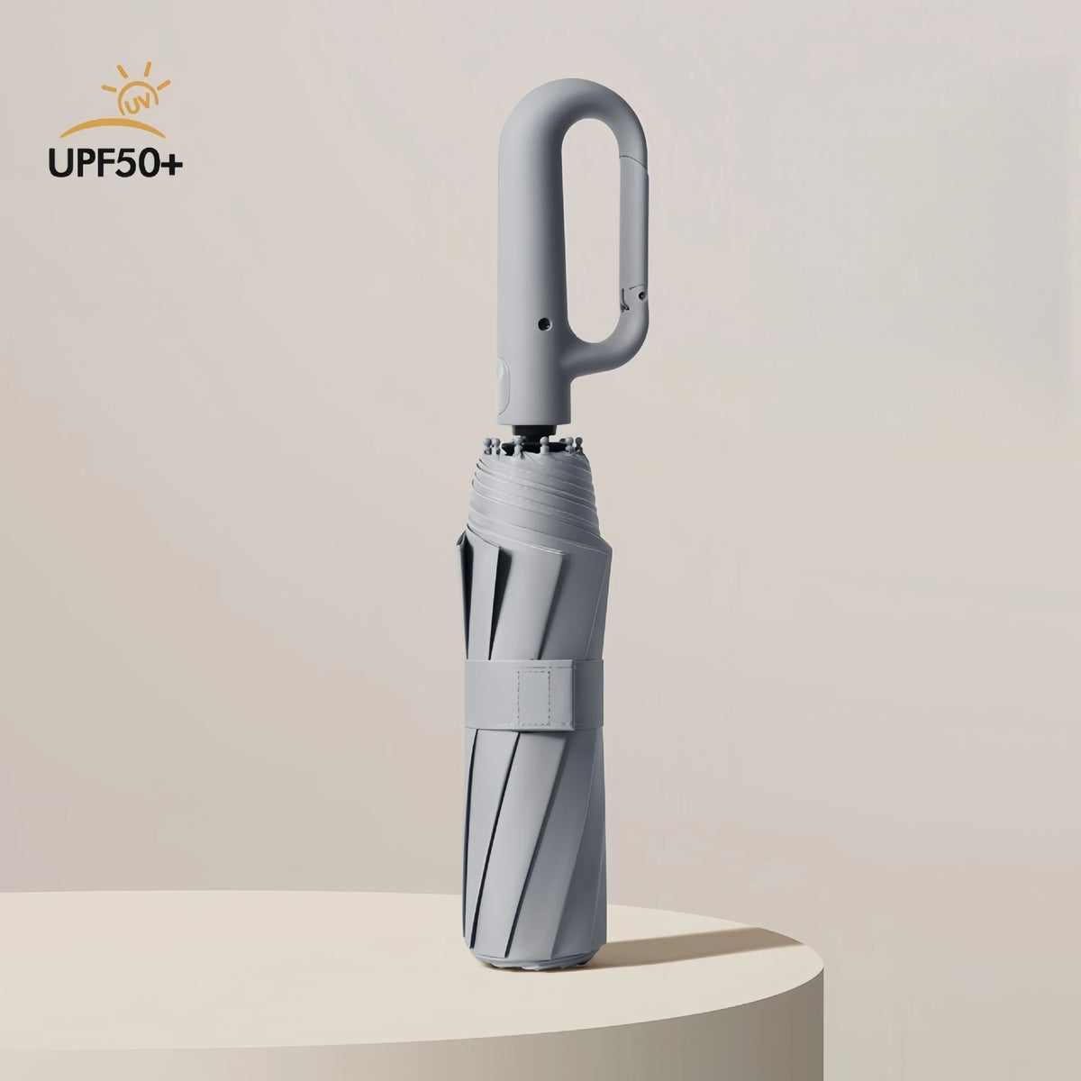 A silver windproof automatic folding umbrella standing upright on a light surface.