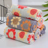 A stack of colorful kitchen cleaning cloths featuring floral patterns in shades of orange, pink, and gray.