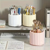 A set of pink and cream cylindrical organizers holding various makeup brushes and tools on a desk.