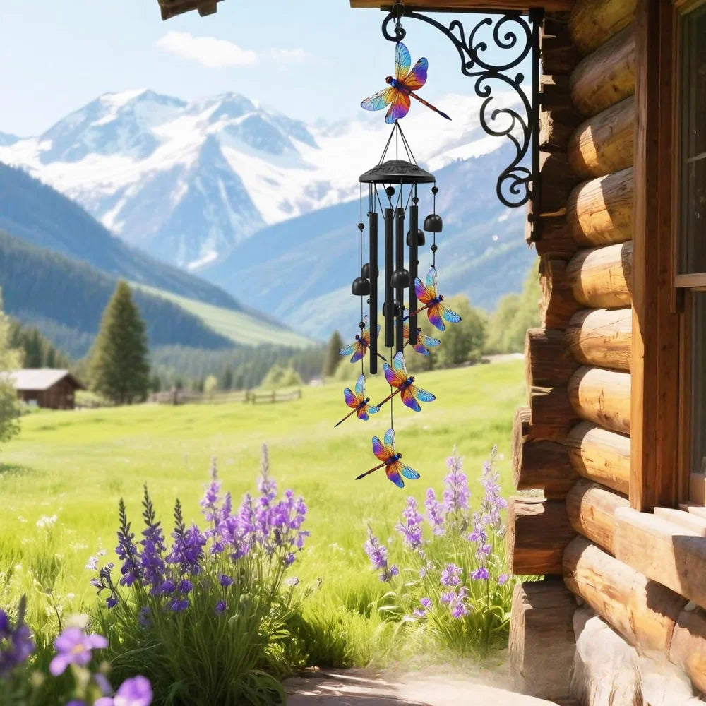Handcrafted metal wind chime decoration hanging by a window with a mountain landscape in the background