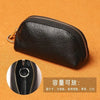 Black leather key organizer wallet with a zipper closure shown on an orange background.