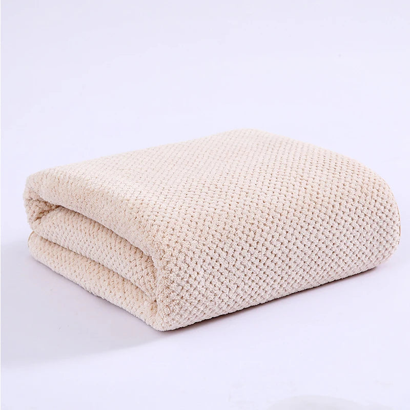 A beige thickened microfiber bath towel folded and displayed on a white background.