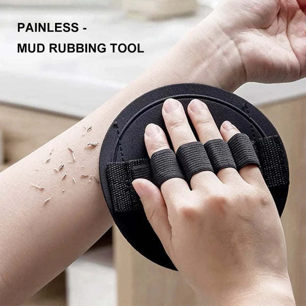 A hand is using a black mud rubbing tool on its wrist to exfoliate the skin.