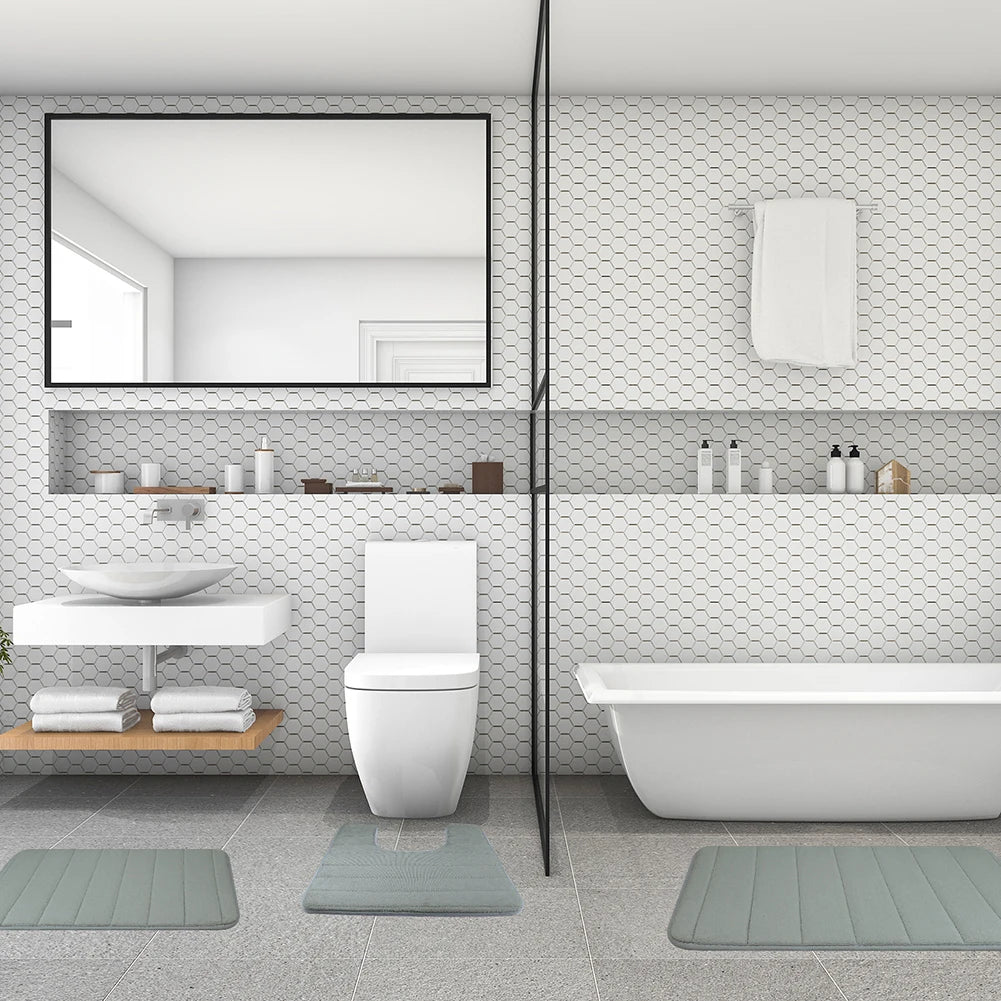Weißes Badezimmer mit Toilette, Waschbereich und Badewanne mit drei grauen Schaumstoffteppichen