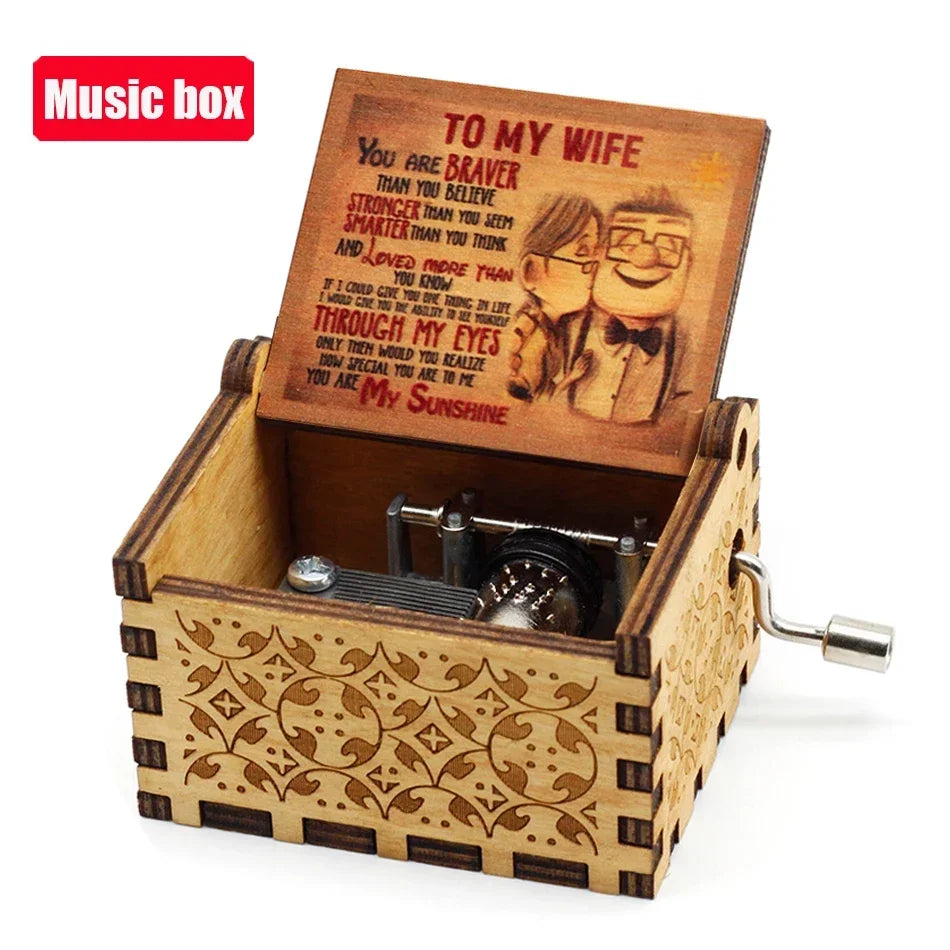 An antique wooden hand crank music box with an engraved lid featuring a romantic message.