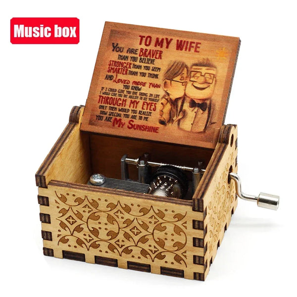 An antique wooden hand crank music box with an engraved lid featuring a romantic message.