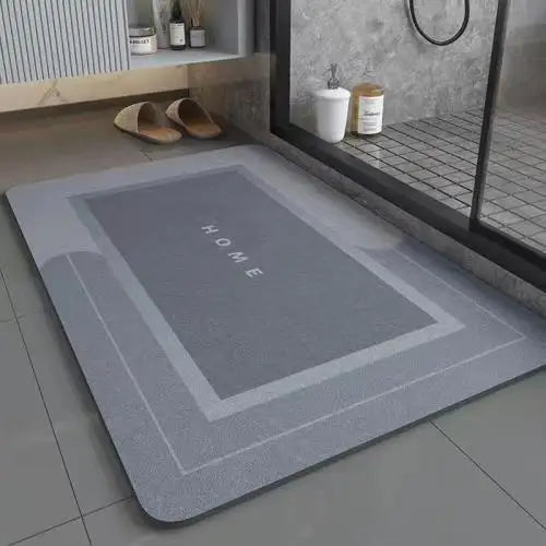 A gray anti-slip floor mat with the word HOME printed on it placed on a tiled floor.