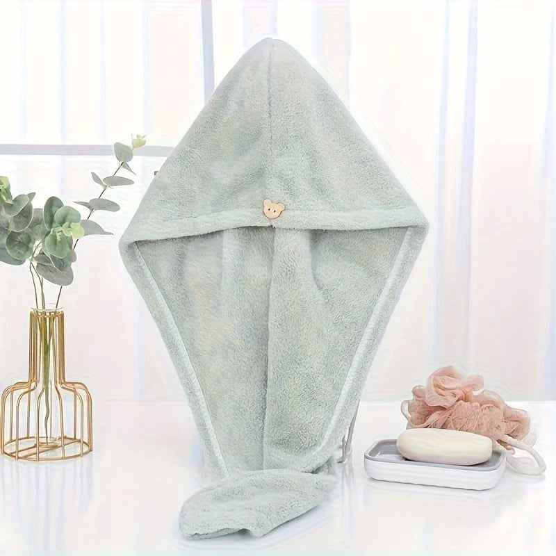 A light mint green microfiber hair drying wrap towel with a small bear charm displayed on a white surface.