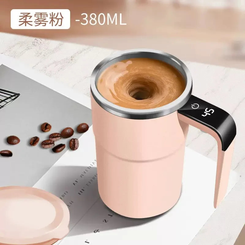 A pink electric self-stirring coffee mug with a silver lid is shown next to coffee beans on a white surface.