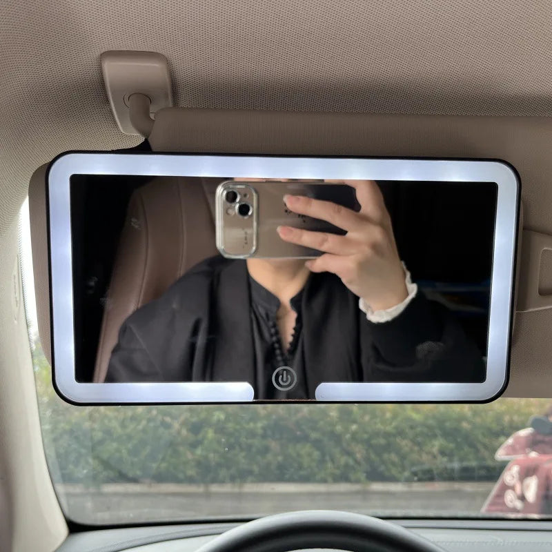 Espejo de maquillaje con luz LED montado en la ventana de un coche, mostrando a una persona usando un smartphone para tomar u