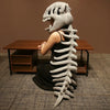 A realistic dinosaur skeleton costume featuring a large skull and vertebral column displayed on a wooden table.