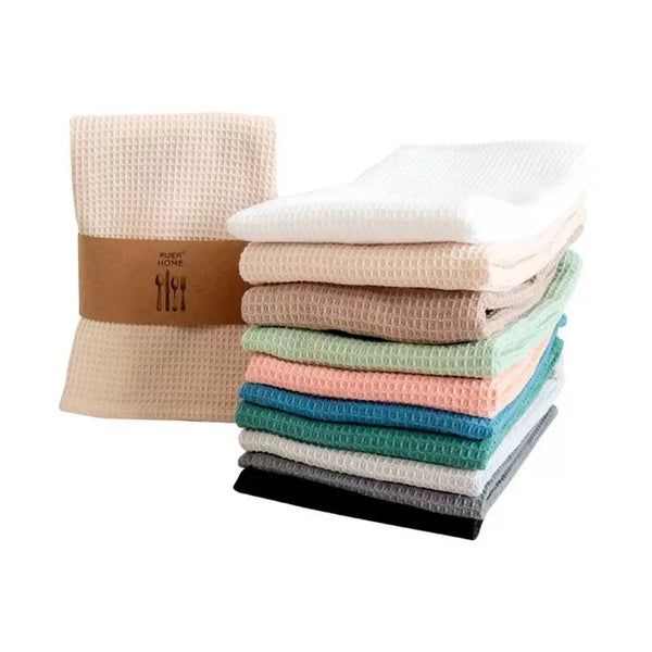 A stack of four absorbent 100% cotton waffle weave towels in various pastel and muted colors.