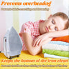 A woman rests her head on a stack of fabric and an iron with a protective cover shield.