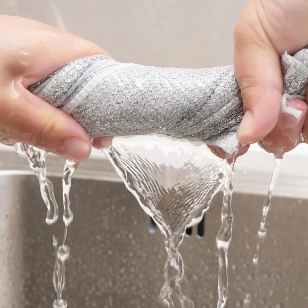 Hands are holding a gray non-stick wire cleaning dish rag that is dripping water.