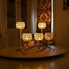 A set of four gold crystal tealight candlesticks displayed on a wooden surface.