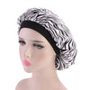 A woman wearing a black satin sleep bonnet with a zebra print fabric.