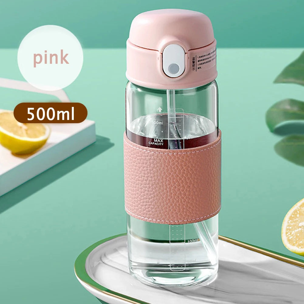 Une tasse en verre rose portable avec couvercle et balance à côté d'un citron sur une surface verte.