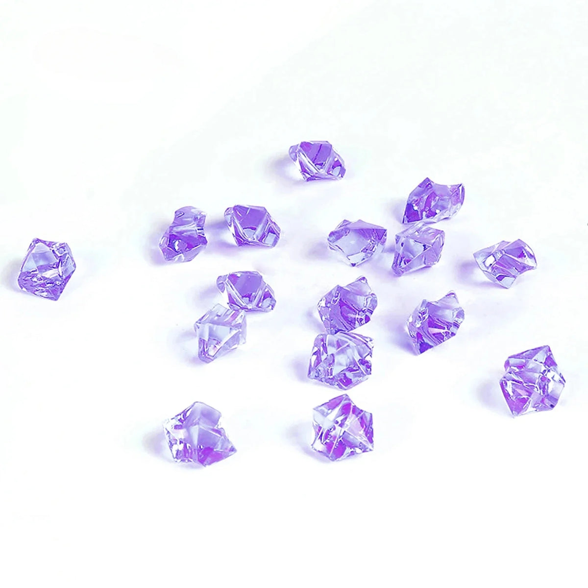 A collection of crushed purple crystal ice stones scattered on a white background.