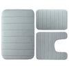 A set of three gray memory foam bathroom rugs, including a rectangular mat and two irregular shapes.