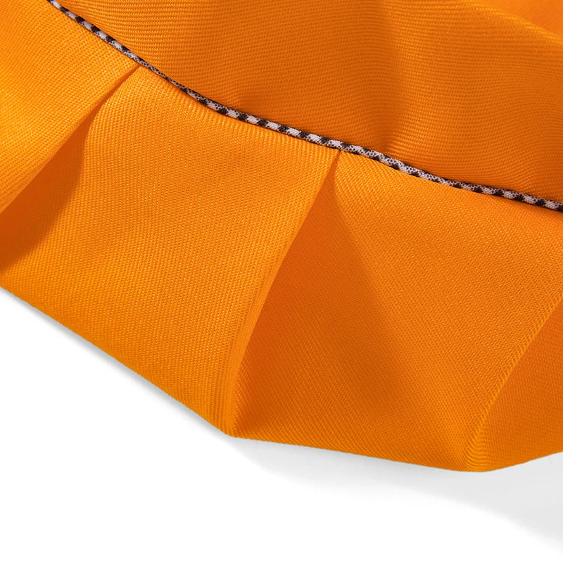Orange fabric of a kids' adjustable apron and chef hat set shown in a close-up view.