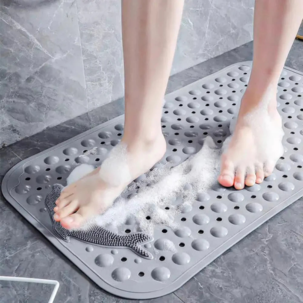 A person's feet are placed on a gray rectangular non-slip bath mat, which is covered in white exfoliating powder.