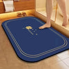 A dark blue diatomite bath mat with a gold floral design placed on a tiled bathroom floor.