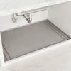 A silicone under sink waterproof mat is installed in a kitchen cabinet, positioned beneath a stainless steel sink.