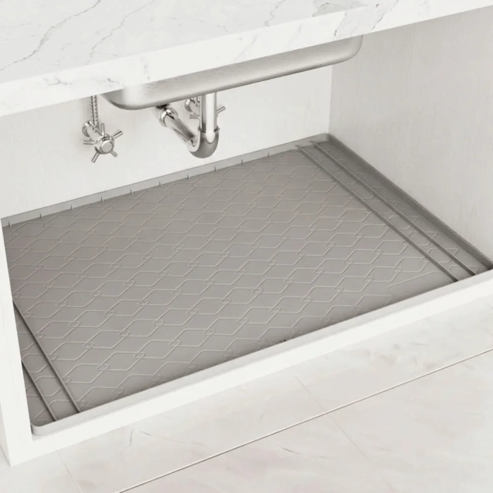 A silicone under sink waterproof mat is installed in a kitchen cabinet, positioned beneath a stainless steel sink.