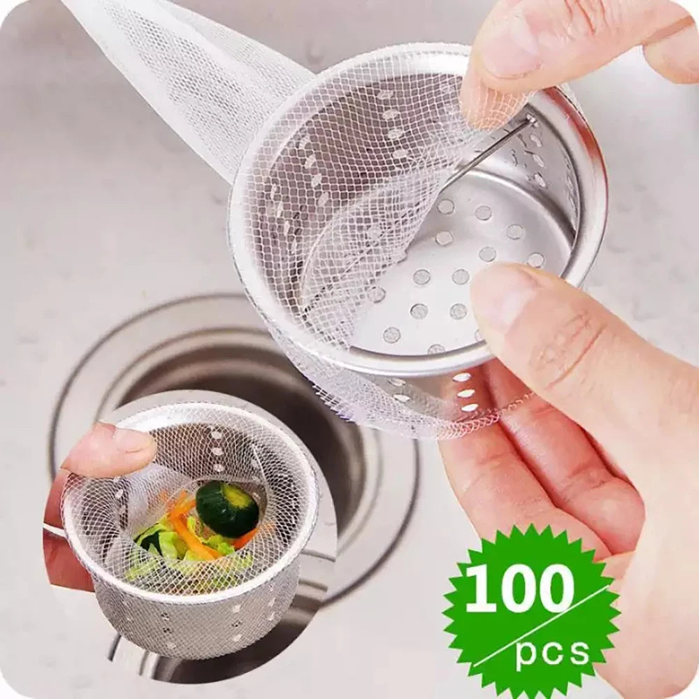 A hand is holding a reusable mesh strainer bag with holes, positioned over a kitchen drain.