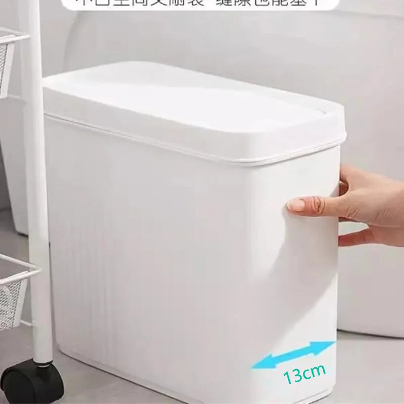 A white slim bathroom trash can with a press lid is shown being held by a hand.