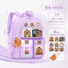 A purple school backpack featuring various capybara-themed accessories and charms for children.