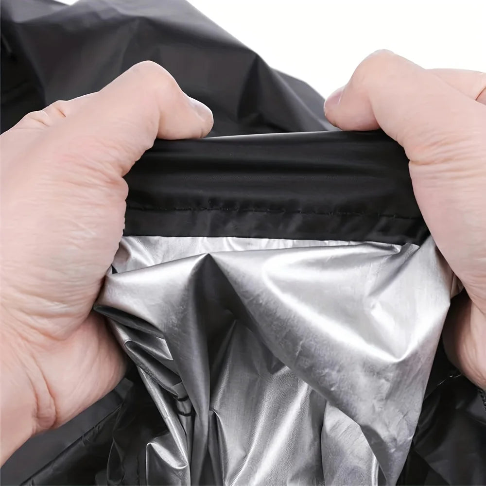 Hands holding a heavy-duty protective cover for a lawn mower, showing the silver inner layer.