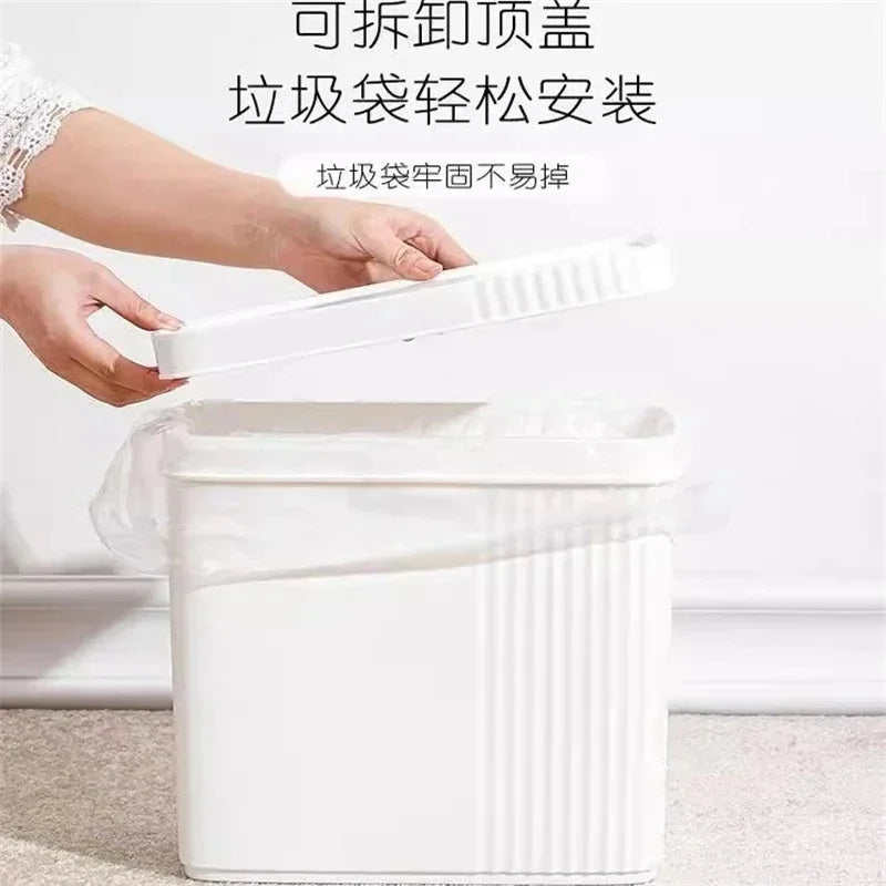A hand is shown pressing the lid of a white slim bathroom trash can, demonstrating its press-lid feature.
