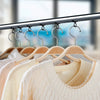 A row of light beige knitted sweaters hanging on a metal rack with silicone self-adhesive hangers.