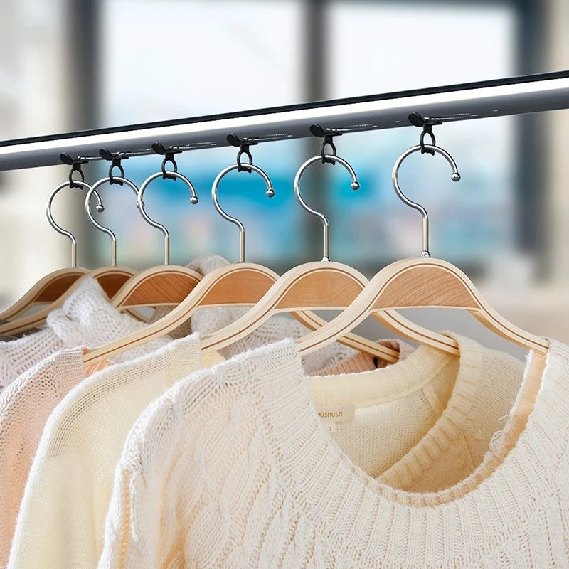 A row of light beige knitted sweaters hanging on a metal rack with silicone self-adhesive hangers.