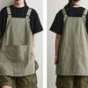 A person wearing a khaki green waterproof outdoor work apron over a black shirt and olive pants.