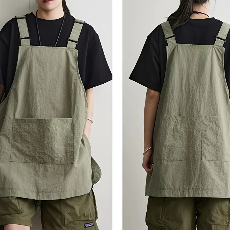 A person wearing a khaki green waterproof outdoor work apron over a black shirt and olive pants.