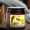 A dark brown glass jar with a black lid containing a candle, featuring a photo space for customization.