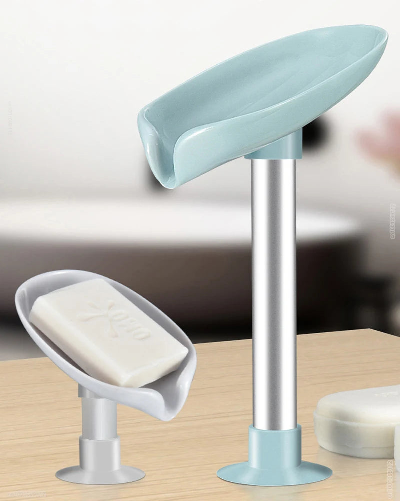 A light blue leaf-shaped suction cup soap dish with a silver stand and white bar soap.