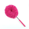 A bright pink, fluffy microfiber duster with a handle is shown against a white background.