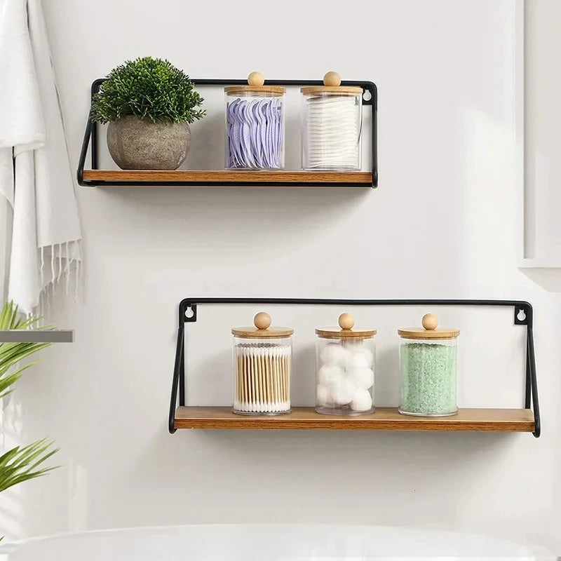 A black wooden shelf holds three apothecary jars with lids filled with lavender, white, and green bath salts.
