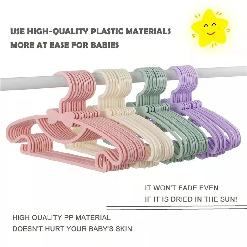 A display of pink, beige, green, and purple plastic clothes hangers for babies and kids.