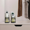 A pair of clear plastic shoe racks with white shoes are displayed on a shelf next to a hanging garment.