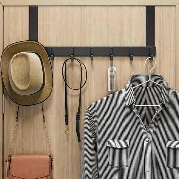 A wooden coat rack with six hooks displaying a brown hat and a striped shirt.