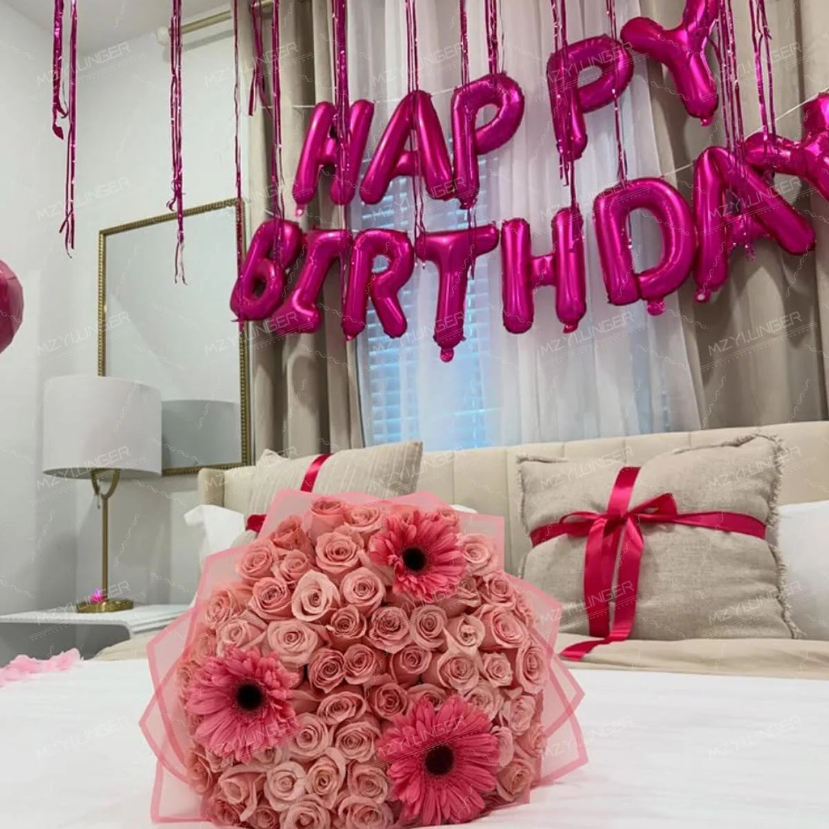 A pink heart birthday balloon set hangs above a bed with sheer curtains and a large mirror.