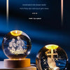 A set of illuminated crystal balls resting on wooden bases, featuring scenes and a cross.