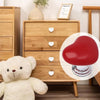Bouton de chasse d'eau en forme de cœur rouge à côté de meubles en bois et d'un ours en peluche.