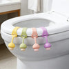 A set of colorful silicone toilet seat lifter rings with yellow, green, pink, and purple colors displayed on a white toilet b