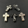 Three silver-toned cross pendants made of marbled white and gray stone resting on a dark surface.